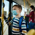 Bild eines Kindes mit Mund-Nasen-Schutz in einer Straßenbahn.