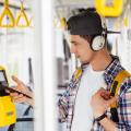 Junger Mann bezahlt mit seinem Handy an einem Ticketautomaten in einer Straßenbahn.