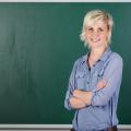 Eine Lehrerin steht vor einer grünen Tafel in einem Klassenraum