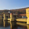 Ein Wasserkraftwerk an einem Fluss mit Schiffen im Hintergrund