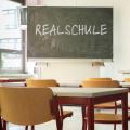 Ein Klassenraum mit einer Tafel auf der das Wort Realschule steht.