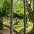 Abgebildet ist ein abgeschlossener Friedhof in naturnaher Umgebung. 