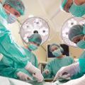Ein Team aus Ärztinnen und Ärzten operiert eine Person in einem Operationssaal. 