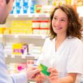 Eine Pharmazeutisch-Technische Assistentin nimmt in einer Apotheke die Gesundheitskarte eines Kunden entgegen. 