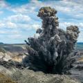 Abgebildet ist eine Explosion auf einem großen Gelände im Tagebau. 