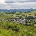 Abgebildet ist das Panorama eines Dorfs in ländlicher Umgebung. 