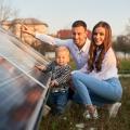 Eine dreiköpfige Famile (Vater, Mutter, Kind) untersucht eine Photovoltaikanlage.