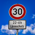 Abgebildet ist ein Tempo-30-Straßenschild. Unter dem Schild ist ein weiteres Schild angebracht, dass darauf hinweist, dass zwischen 22 Uhr und 6 Uhr Lärmschutz beachtet werden muss. 