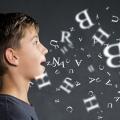 Eine Junge steht seitlich vor einer Tafel, aus seinem Mund strömen Buchstaben.