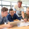 Eine Lehrer und eine Gruppe Schüler*innen mit Tablet und technischer Zeichnung.