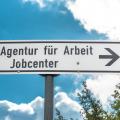Abgebildet ist ein Straßenschild mit der Aufschrift "Agentur für Arbeit - Jobcenter".