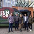 Fünf Personen stehen vor einem Transporter mit der Beschriftung Museum Mobil vor dem Haupteingang der Bezirksregierung.