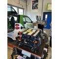 Abgebildet sind ein Elektroauto und eine ausgebaute Batterie in einer Werkstatt. 