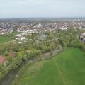Blick von oben auf eine Flusslandschaft mit Wohnbebauung im Hintergrund