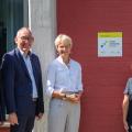 Die Personen stehen vor einem Gebäude mit der angebrachten Plakette.