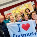 Abgebildet sind mehrere Personen, die für ein Bild posieren. Sie halten eine Flagge mit der Aufschrift "I love Erasmus+" (zu Deutsch: "Ich liebe Erasmus+") hoch.