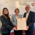 Heinrich Böckelühr präsentiert mit Heike Weiß (Mitte), Leiterin der Abteilung Pflege und Alter beim Ministerium für Arbeit, Gesundheit und Soziales NRW, und Anahita Roßmann, Leiterin des Büros des Regierungspräsidenten, die Charta zur „Vereinbarkeit von Beruf & Pflege“.