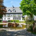 Abgebildet ist ein Fachwerkhaus in idyllischer Umgebung. Im Vorgarten des Hauses befindet sich ein Teich.