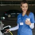 Abgebildet ist eine Pflegefachkraft, die ein Elektroauto in einer Tiefgarage lädt und gleichzeitig auf ihr Handy schaut.