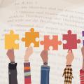 Abgebildet sind Puzzlestücke in verschiedenen Farben, die nebeneinander hochgehalten werden. Im Hintergrund ist der Inhalt von Artikel 3 Absatz 1 Grundgesetz abgebildet.